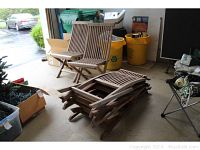 Two wooden folding deck chairs set up with six folded stacked chairs behind, showing overall condition and size.