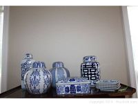 Front view of four covered ginger jars, a covered box, and four small plates on a wooden tray.