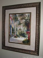 View of the larger framed tropical garden print with ornate dark brown/gold frame and beige mat.