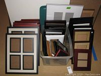 Overall view of large variety of picture frames stacked and arranged in storage boxes and on floor