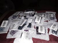 Top view of 15 individually packaged Fitbit watch covers laid out to show variety in patterns and quantity.