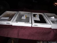 Four phone cases in retail packaging laid out side-by-side on a red cloth surface.