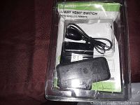 Front view of the Belkin 4-Way HDMI Switch package with remote and power adapter visible inside plastic clamshell.