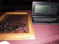 Framed footprint picture on table with Radio Shack Talking Organizer open on right