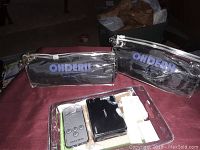 Two Ohderll-branded clear plastic pouches with media players and HDMI switch on table in room