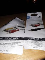 Two black packaged cables, a composite AV cable with red, white, yellow connectors and a 3.5mm AUX to RCA stereo audio cable.