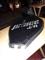 Black vinyl racquet cover with 'Prince JR' printed in white and the racquet handle partially visible.