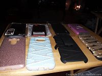 Photo of 8 assorted phone cases laid out on a table showcasing different colors and styles including glittery, textured, folio, and belt clip holster designs.