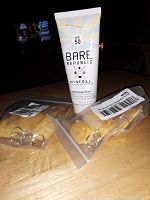 Tube of Bare Republic SPF 50 Mineral Sunscreen Lotion next to a sealed bag of yellow plastic ID tags with key rings.
