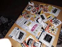 Image of assorted phone and alkaline batteries in sealed retail packaging on a wooden table.