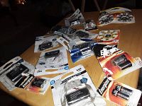 Photo showing a variety of new, sealed battery packs from Energizer and ONN on a wooden table.