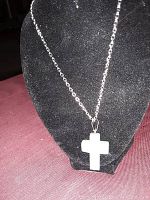 Front view of silver chain necklace with white jade cross pendant displayed on black bust stand.