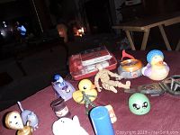 Photo showing a variety of children's toys including rubber ducks, action figures and small novelty items, displayed on a table.