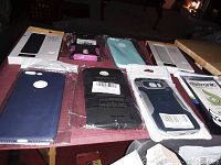 Top view of eight phone cases laid on a table showing various colors and packaging, including boxed and sealed plastic.