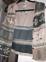 Photo of wool blend knitted vest hanging on a black hanger showing front with Nordic patterns and button closure.