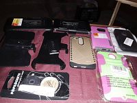 Photo showing black plastic phone holder and six assorted phone cases in various colors and styles arranged on a table. Also included is a packaged Pro-Care Sports item with adhesive tape or pads.