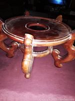 Side angle showing the circular top with central hole and four curved carved legs.