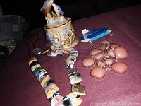 Image of ceramic keepsake container and two necklaces on a dark cloth background