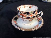 Tea cup and saucer set viewed from front side on a black background to display pattern and colors.
