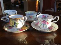 Top view of 4 Royal Albert tea cups with matching saucers showing floral designs and gold accents