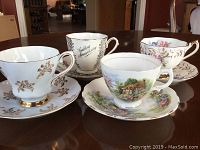 Four signed and numbered tea cups and matching saucers on a table.
