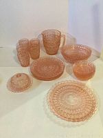 Full lot assortment of pink pressed glass dinnerware including glasses, pitcher, platter, bowls, plates, and butter dish in diamond cut pattern.