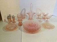 Full lot view showing all pink glass items including candy dish, plates, salt and pepper shakers, small glass cups and container.