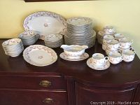 Full set of Bavaria Schumann Original Bridal Rose china displayed on a dark wood surface. Includes stacks of plates, bowls, cups, saucers, two large oval platters, and gravy boat.
