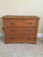 Front view of vintage wooden dresser showing three drawers and brass handles