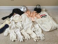 Full lot showing vintage gloves, two purses, a hat and a cream colored sleepwear or lounge dress