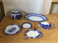 Overview of entire lot with various blue and white porcelain dishes and vase displayed on wooden surface