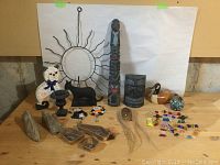 Full view of lot including various figurines, sculptures, glass candies and a metal sun wall art.