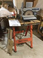 Full view of the Mastercraft belt and disc sander on the orange Saw Table stand, showing the entire unit on a wooden top with accessories placed beside it.