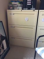 Front view of the beige 3 drawer lateral file cabinet with lock and label holders on drawers.