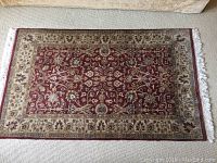 Full view of rectangular red and beige wool carpet laid on floor