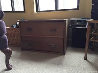 Front view of antique two-drawer wooden chest showing wood grain finish and metal drawer pulls.