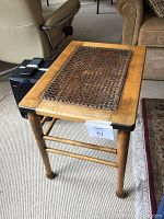 Front angle view of the antique side table showing wooden frame and caned top insert.