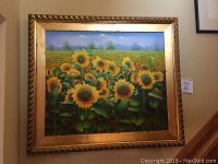 Full view of the framed oil painting of sunflowers on canvas hung on a wall.