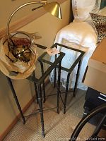 LED-lit brass desk lamp with curved arm and conical shade, shown with two different sized side tables with metal bamboo-style bases and glass tops.