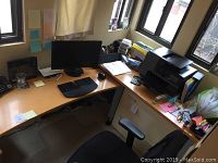 L-shaped desk system showing computer desk with monitor, keyboard, mouse, and printer desk with large printer and office supplies.