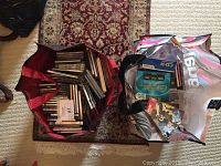 Overhead image showing two bags filled with assorted CDs in jewel cases. One bag is a red fabric tote, the other a plastic shopping bag.