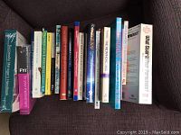 Photo showing a collection of 13 self help and professional development books on a dark brown fabric surface.