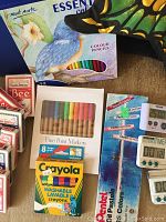 Close up of art supplies, colour pencils, markers, crayons, playing cards and digital timers arranged on a surface