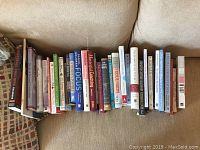 Photo of 13 assorted self-help, leadership, and coaching books arranged side by side on a couch.