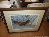 Framed artwork showing bird in snow scene, wood frame, double matting