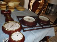 Three-piece set including Bios barometer with thermometer, decorative clock, and thermometer on table