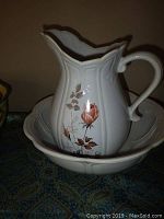 White ceramic McCoy pitcher and matching bowl with floral rose design, scalloped edges and embossed vertical panels.