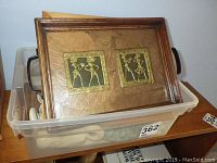 Plastic bin containing two small framed prints with dancing female figures and detailed metalwork on the frames