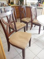 Four wooden kitchen dining chairs positioned in a kitchen area showing overall design and condition.