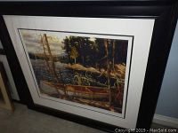 Framed print showing canoe on lake scene with black frame and white mat